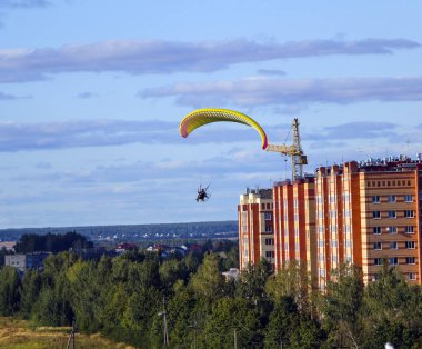 Motor paraplan uçuşu. parlak renkli motoparaplane Köyü, alan ve inşaat site yukarıda adam uçar.