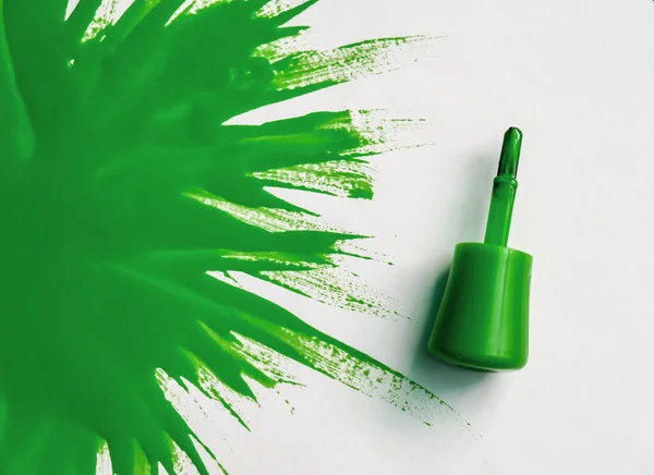 green nail polish. explosion of color. Brush with green nail polish with large spot of varnish on  white background.