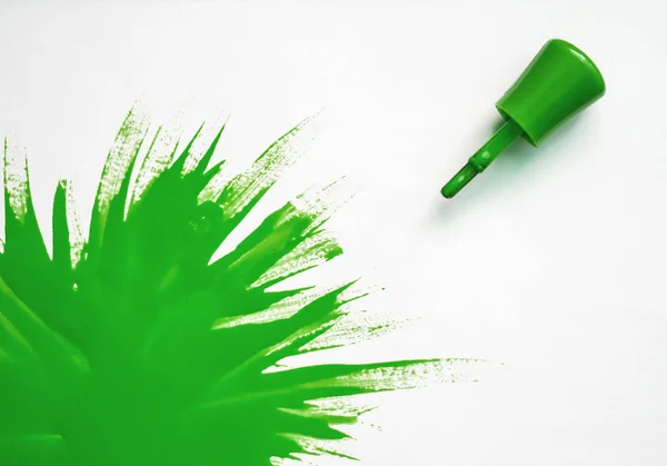 green nail polish. explosion of color. Brush with green nail polish with large spot of varnish on  white background.