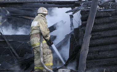 İtfaiye yangını söndürür. Ahşap yapı duman içinde yanan güçlü akış sulama hortumu su ile tutarak itfaiyeci.