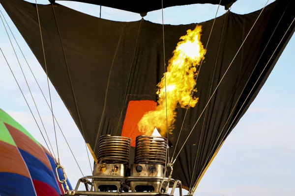 Hot air balloon being inflated for flight. Gas burner fills canopy of balloon with hot air. Pumping fire to apply hot air into fireproof air-balloon. Hot air balloon burner heating air with fire.