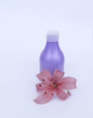 Kozmetik Cilt bakımı için zambak çiçekler ile beyaz bir arka plan üzerinde ayarlayın. kompozisyon Spa, banyo, sauna, duş için. Lila duş şampuan ve duş jeli ile yumuşak cilt temizliği için mor lily.