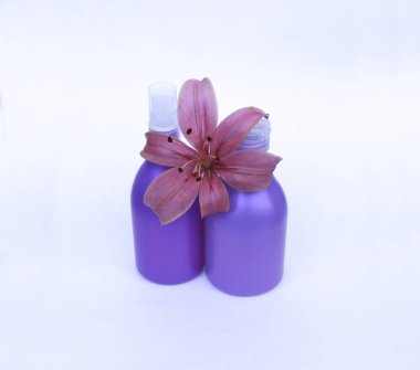 Kozmetik Cilt bakımı için zambak çiçekler ile beyaz bir arka plan üzerinde ayarlayın. kompozisyon Spa, banyo, sauna, duş için. Lila duş şampuan ve duş jeli ile yumuşak cilt temizliği için mor lily.