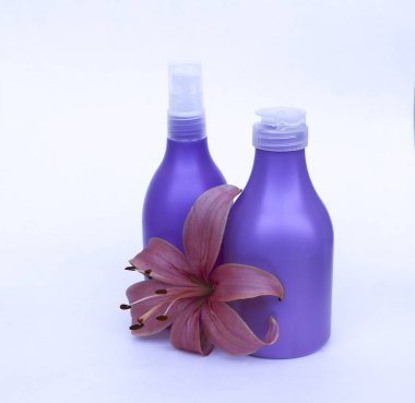 Kozmetik Cilt bakımı için zambak çiçekler ile beyaz bir arka plan üzerinde ayarlayın. kompozisyon Spa, banyo, sauna, duş için. Lila duş şampuan ve duş jeli ile yumuşak cilt temizliği için mor lily.