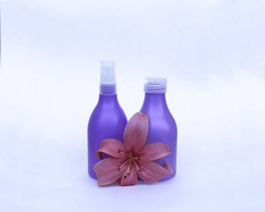 Kozmetik Cilt bakımı için zambak çiçekler ile beyaz bir arka plan üzerinde ayarlayın. kompozisyon Spa, banyo, sauna, duş için. Lila duş şampuan ve duş jeli ile yumuşak cilt temizliği için mor lily.
