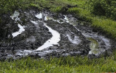 kirli ülke yol ıslak toprak, imkansızı. çamur ve su birikintileri toprak yol üzerinde. Traktörler ve otomobil izlemeler.