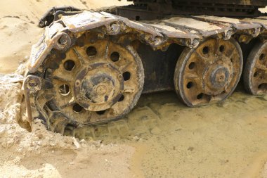 ıslak kum eski demir tırtıl. Paslı çelik jantlar ve caterpillar teyp büyük buldozer, tank, ekskavatör, nemli kum ve su birikintileri.