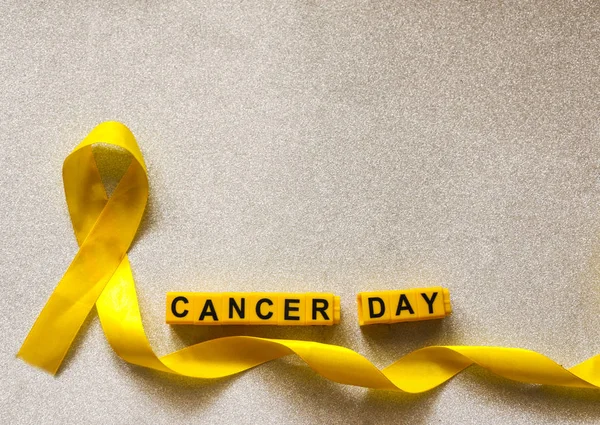 golden ribbon and words made up of children\'s plastic beeches. concept - a symbol of childhood cancer, pediatric oncology.
