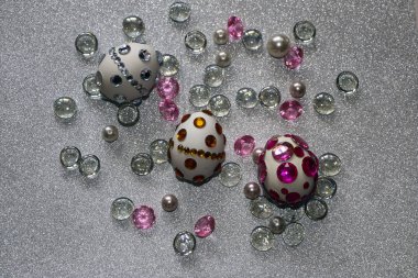 Paskalya kompozisyon flatlay. Paskalya yumurtaları Cam süsler ve inci boncuk gümüş bir arka plan üzerinde parlak rhinestones ile dekore edilmiştir.