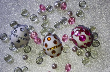 Paskalya kompozisyon flatlay. Paskalya yumurtaları Cam süsler ve inci boncuk gümüş bir arka plan üzerinde parlak rhinestones ile dekore edilmiştir.