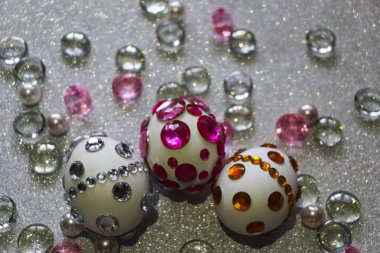 Paskalya kompozisyon flatlay. Paskalya yumurtaları Cam süsler ve inci boncuk gümüş bir arka plan üzerinde parlak rhinestones ile dekore edilmiştir.