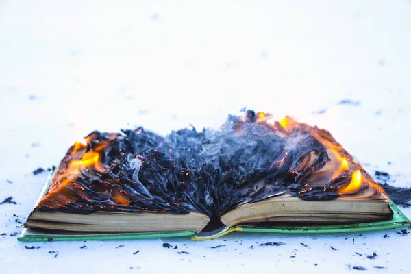 Livro em chamas na neve. páginas com o texto em livro aberto queimar wi — Fotografia de Stock