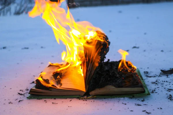 Livro em chamas na neve. páginas com o texto em livro aberto queimar wi — Fotografia de Stock