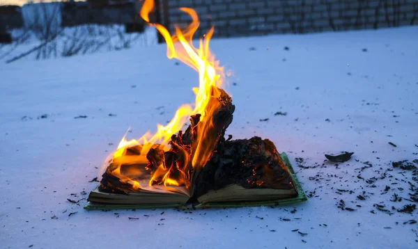 Burning book in  snow. pages with the text in  open book burn wi — Stock Photo, Image
