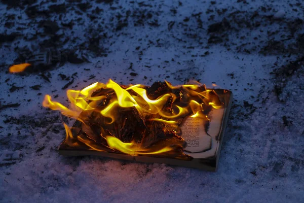 Burning book in  snow. pages with the text in  open book burn wi — Stock Photo, Image