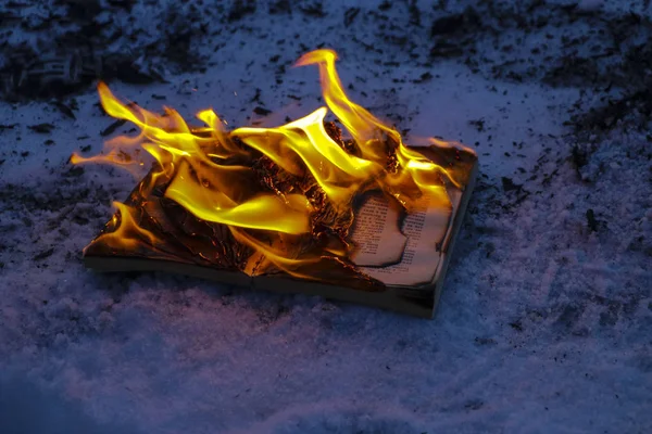 Brinnande bok i snö. sidor med texten i öppen bok bränna wi — Stockfoto