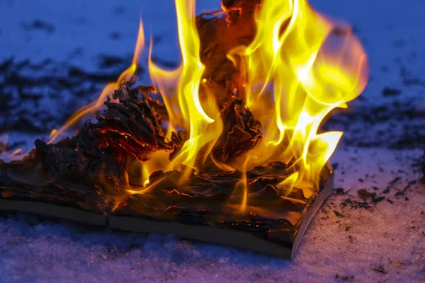 Brinnande bok i snö. sidor med texten i öppen bok bränna wi — Stockfoto