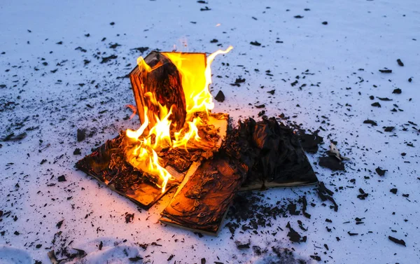 Палаюча книга в снігу. сторінки з текстом у відкритій книзі спалюють wi — стокове фото
