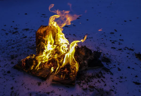 Brinnande bok i snö. sidor med texten i öppna bok bränna med ljusa lågan. — Stockfoto