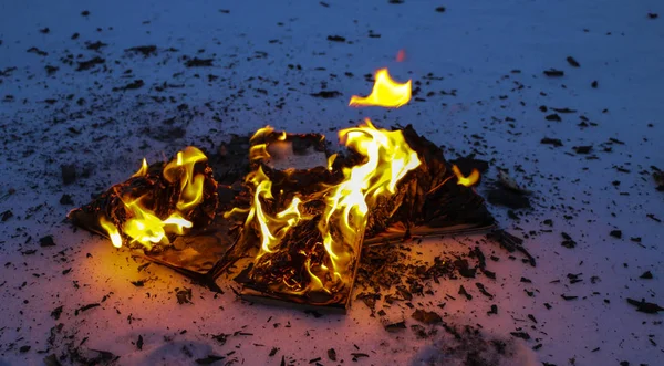 Livro em chamas na neve. páginas com o texto em livro aberto queimar wi — Fotografia de Stock