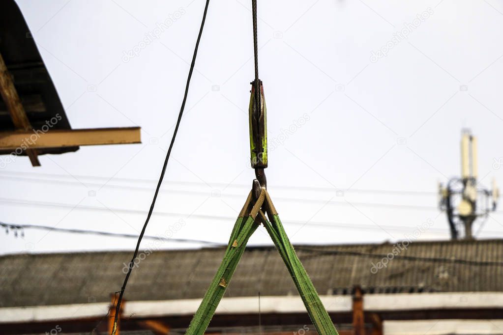 old girder crane with large iron hook lifts  heavy load on  slings