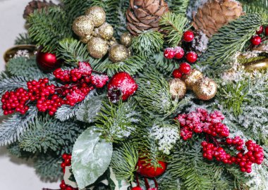 Çamın dalları, altın Noel süsleri, kırmızı meyveler ve yapay kar Noel bileşimi.