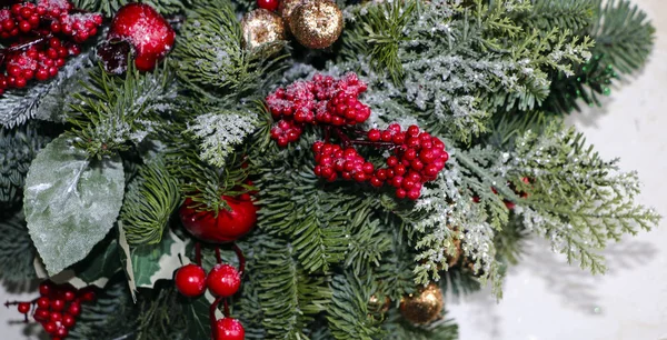 Vánoční složení borové větve, zlaté vánoční ozdoby, červené bobule a umělý sníh. — Stock fotografie