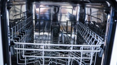 açık kapı ile bulaşık makinesi vardır. çatal bıçak takımı için yemek ve sepet dağıtımı için bulaşık makinesinin iç rafları.