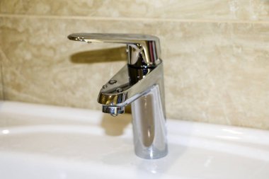 banyo parlak krom kaplamalı musluk, su damlaları ile.