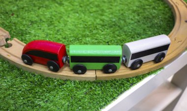 Yapay plastik yeşil çimenler üzerinde arabalar, demiryolu ve ahşap ağaçlar ile çocuk ahşap tren. Erken çocukluk eğitimi, okul öncesi ve çocuk oyun konsepti.