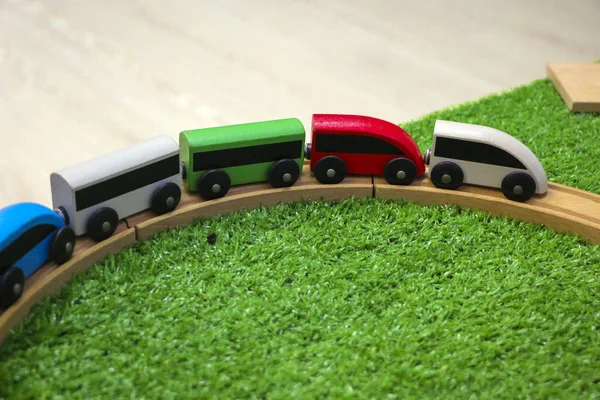 Детский деревянный поезд с автомобилями, железнодорожными и деревянными деревьями на искусственной пластиковой зеленой траве. Концепция дошкольного воспитания, детских садов и игр для детей . — стоковое фото