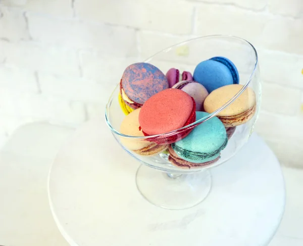 Macarrones de colores brillantes y mármol en jarrón de vidrio sobre fondo de ladrillo blanco . — Foto de Stock