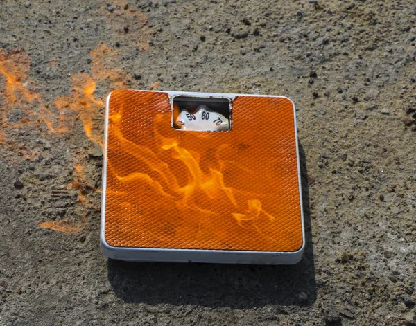 Burning floor scales on asphalt textural background. concept - burning calories, slimming and losing weight through diets and sports exercises.