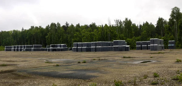 Los productos terminados de botellas limpias se embalan en paletas. Bastidores con botellas están en área abandonada cerca de la fábrica de vidrio cerca del bosque . — Foto de Stock