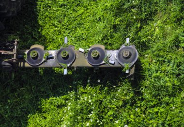 Tarım salatıcısı sırasında traktör için monte edilmiş disk biçme makinesi, hızlı dönüş sırasında sulu yeşil çim çim biçiyor.