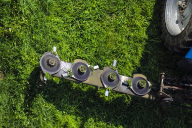 Tarım salatıcısı sırasında traktör için monte edilmiş disk biçme makinesi, hızlı dönüş sırasında sulu yeşil çim çim biçiyor.