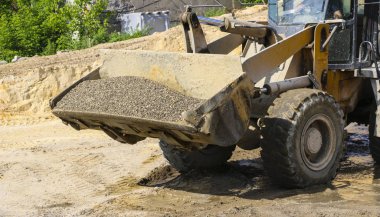  traktör çakıl ile kepçe toplar. beton karışımı için ekskavatör ayıklar kum ve çakıl.