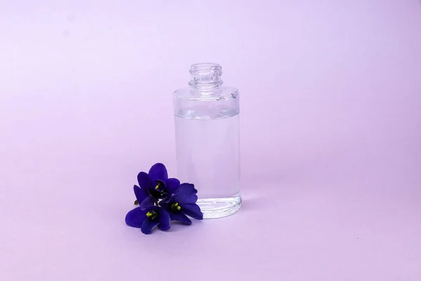 Liquide en bouteille transparente avec pipette pour planer cigarettes électroniques avec parfum et goût de fleurs, sur fond rose avec espace pour le texte . — Photo