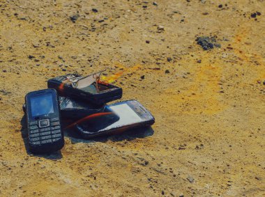 dokusal beton arka plan üzerinde yanmış cep telefonları. Konsept: Düşük kaliteli cep telefonları kullanma tehlikesi.