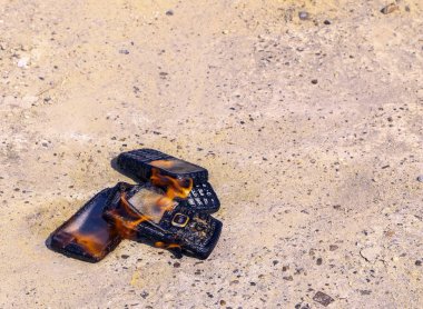 dokusal beton arka plan üzerinde yanmış cep telefonları. Konsept: Düşük kaliteli cep telefonları kullanma tehlikesi.