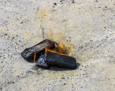 dokusal beton arka plan üzerinde yanmış cep telefonları. Konsept: Düşük kaliteli cep telefonları kullanma tehlikesi.