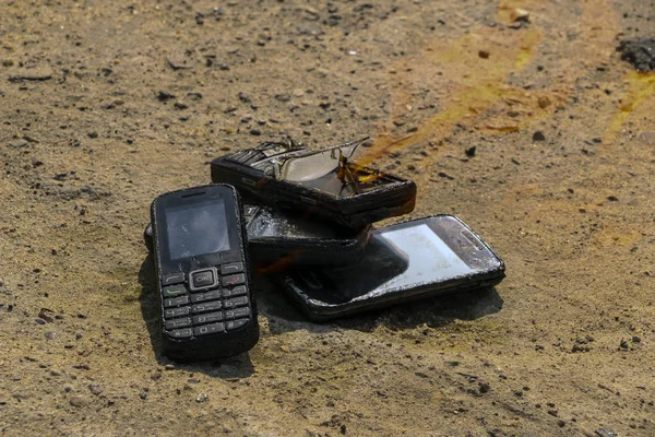 Спалені мобільні телефони на текстовому бетонному фоні. Концепція: небезпека використання низькоякісних мобільних телефонів . — стокове фото
