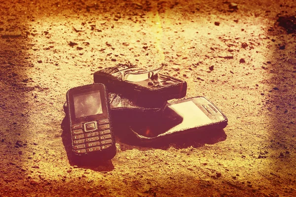 burnt mobile phones on textural concrete background. Concept: Danger of using low-quality cell phones.