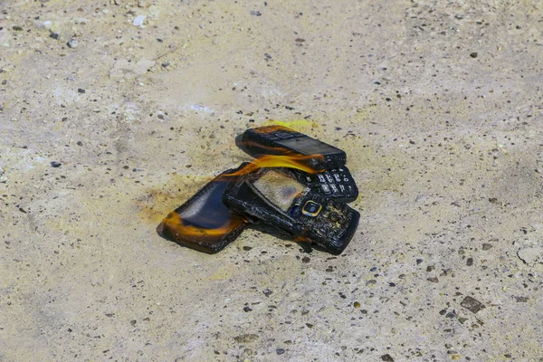 dokusal beton arka plan üzerinde yanmış cep telefonları. Konsept: Düşük kaliteli cep telefonları kullanma tehlikesi.