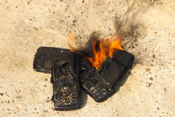 Megégett mobiltelefonok a szöveti konkrét háttér. Koncepció: alacsony minőségű mobiltelefonok használatának veszélye. — Stock Fotó