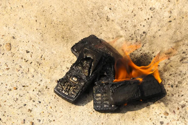 Megégett mobiltelefonok a szöveti konkrét háttér. Koncepció: alacsony minőségű mobiltelefonok használatának veszélye. — Stock Fotó