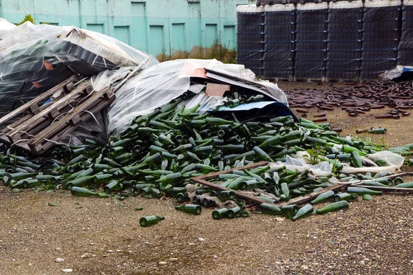 Verlassene Glasfabrik. Flaschen in Paletten, zerbrochene Flaschen auf Asphalt, jede Menge lose Flaschen und Müll aus der Produktion. Verwüstung, Trennung, Konkurs des Unternehmens. — Stockfoto