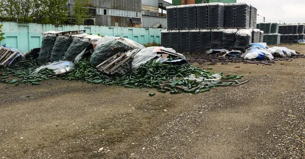 Verlassene Glasfabrik. Flaschen in Paletten, zerbrochene Flaschen auf Asphalt, jede Menge lose Flaschen und Müll aus der Produktion. Verwüstung, Trennung, Konkurs des Unternehmens. — Stockfoto