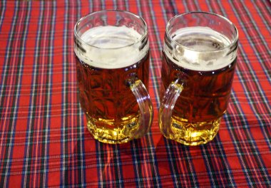 oktoberfest sembolize damalı masa örtüsü üzerinde iki kupa taze bira,.