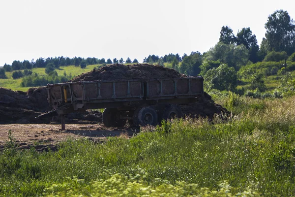 Gammel rustent husvogn med gjødselgjødsel står på jordet for å gjødsle jord før såing . – stockfoto